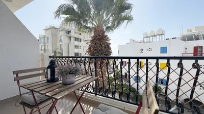 a balcony with a table and a palm tree at Hills 2bdr Seaside Makenzy Larnaka in Larnaka