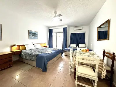 a bedroom with a bed and a table in it at STAY NISSI Chrysland Studios in Ayia Napa