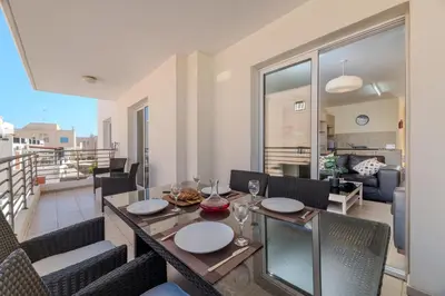 a dining room with a table and chairs and a balcony at Mythical Sands Apartment BA09 in Protaras