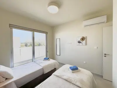two beds in a room with a large window at STAY Mythical Blue Apartment in Protaras