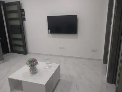 a white room with a television and a white table at Ermioni Apartments in Limassol