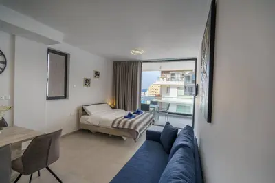 a living room with a blue couch and a table at Seaview Suite49 steps to Mackenzie Beach Larnaca in Larnaka