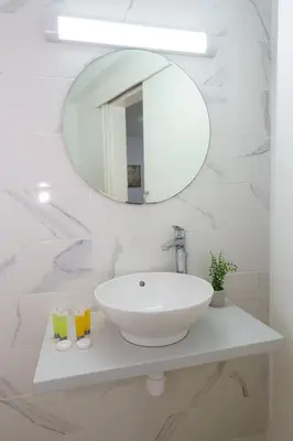 a white bathroom with a sink and a mirror at Kitieos 163 Suite in Finikoudes in Larnaka