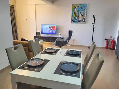 a dining room table with chairs and a laptop at Sunshine Escape in Larnaka