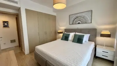 a bedroom with a bed with two green pillows at Zavos Aqua Park Club Apt by TrulyCyprus in Limassol