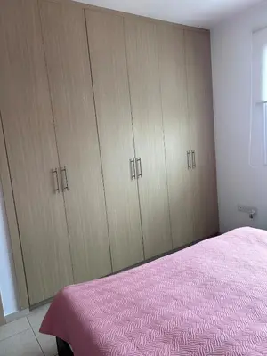 a bedroom with wooden cabinets and a pink bed at Modern Holiday Appartment With Pool in Paralimni