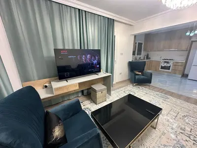 a living room with a blue couch and a flat screen tv at Park Residence Premium in Larnaka