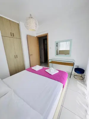 a bedroom with a white bed with a pink blanket at Nissini Wana Luxury Villa in Ayia Napa