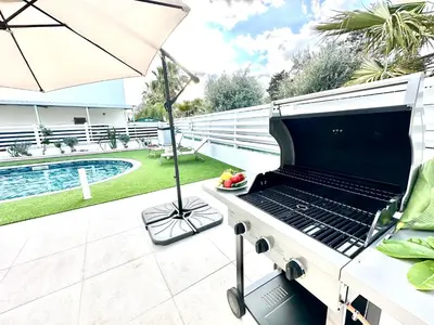 a barbecue grill on a patio with an umbrella at Dream Tropicana Villa - Ayia Napa in Ayia Napa
