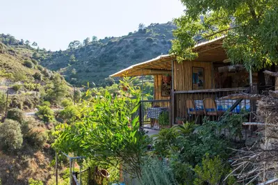 a wooden house with a deck and chairs on a hill at Hatzikyprianou Museum Studio in Lazania