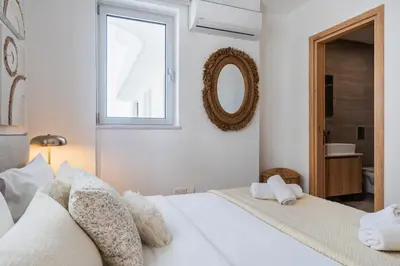 a white bedroom with two beds and a mirror at Aelia - Chic 2-BR Apartment & Balcony in Larnaca in Larnaka