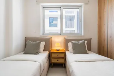 two twin beds in a room with a window at Aelia - Chic 2-BR Apartment & Balcony in Larnaca in Larnaka