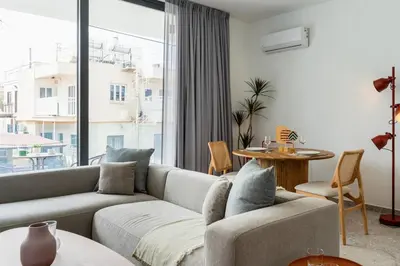 a living room with a couch and a large window at Solara - Stylish Balcony Apartments in Larnaca in Larnaka