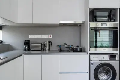a kitchen with white cabinets and a washing machine at Solara - Stylish Balcony Apartments in Larnaca in Larnaka
