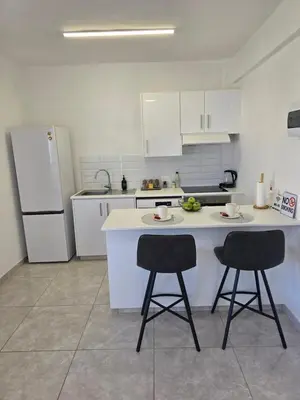 a kitchen with two bar stools and a refrigerator at White Sea View Apartment in Limassol