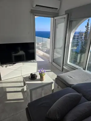 a living room with a couch and a large window at White Sea View Apartment in Limassol