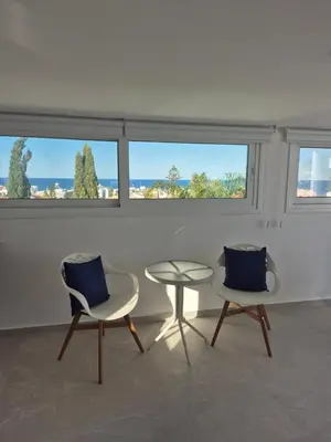 two chairs and a table in a room with windows at Konnos Studio in Protaras