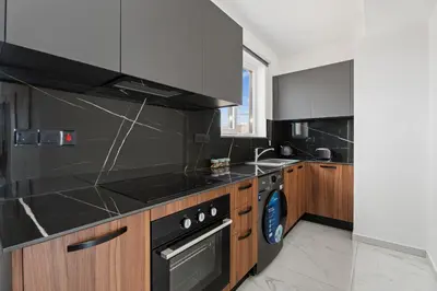 a kitchen with black counters and a sink and a stove at Modern 2BR Apartment Near Ayia Napa - Anastasia 101 in Xylophaghou