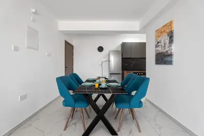 a dining room with a table and blue chairs at Modern 2BR Apartment Near Ayia Napa - Anastasia 101 in Xylophaghou