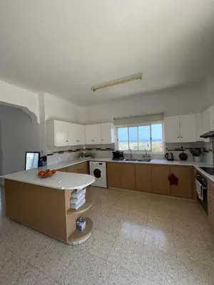 a large kitchen with white cabinets and a table in it at Huge Terrace in peaceful Oroklini in Voroklini