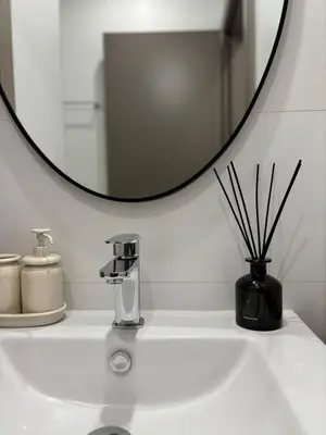 a bathroom sink with a round mirror above it at Best location in Larnaca 100m from the beach in Larnaka