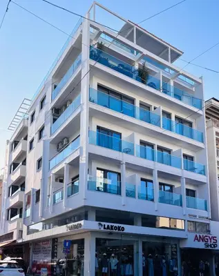 a white building with blue balconies on a street at Best location in Larnaca 100m from the beach in Larnaka