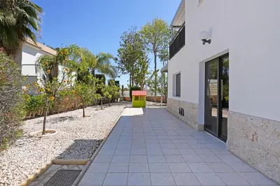 a walkway next to a white building with trees at Villa GreenWay - Large Private Pool in Protaras