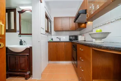 a kitchen with wooden cabinets and a sink and a counter at Seafront central 1 bedroom flat in Limassol
