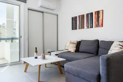 a living room with a couch and a table with wine glasses at Mackenzie Beach Apartment in Larnaka