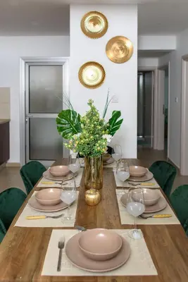 a table with plates and glasses and a vase of flowers at Green Island Apartment 102 in Larnaka