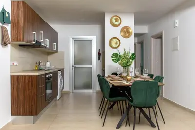 a kitchen and dining room with a table and green chairs at Green Island Apartment 102 in Larnaka