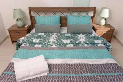a bedroom with a large bed with blue and grey pillows at Green Island Apartment 102 in Larnaka