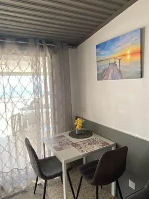 a dining room table with chairs and a picture on the wall at Mackenzie By the sea one bed Ground floor home in Larnaka