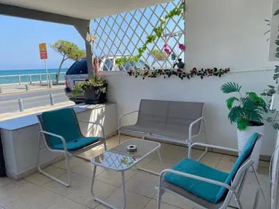 a patio with chairs and a table and a view of the beach at Mackenzie By the sea one bed Ground floor home in Larnaka