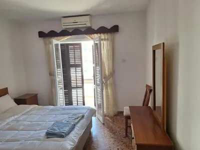 a bedroom with a bed and a table and a window at Big house in center of protaras, near beach in Protaras