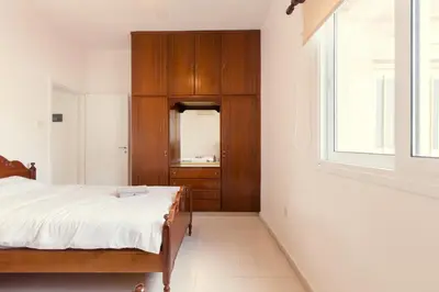 a bedroom with a bed and a wooden cabinet at Spacious Larnaca Beach Apartment in Larnaka