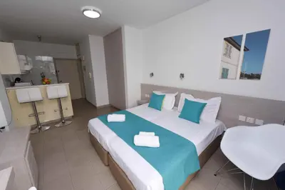 a bedroom with a large bed with blue and white pillows at Finikoudes Sunrise Sea View Lux in Larnaka
