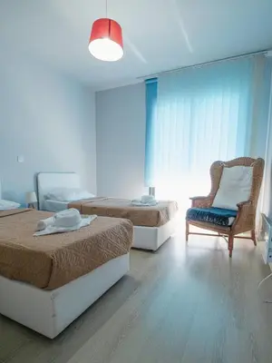 a bedroom with two beds and a chair and a window at Maestro Villa in Meneou