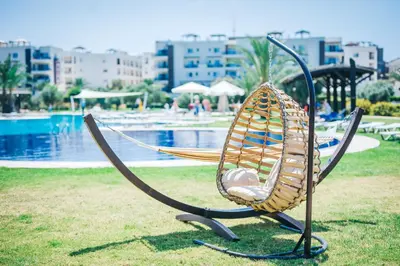 a hammock sitting on the grass near a pool at Cozy apartment at Thalassa Beach Resort, Northern Cyprus in Paralimni