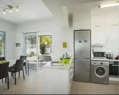a kitchen with a refrigerator and a table with chairs at Sandy Feet Beach House in Paralimni