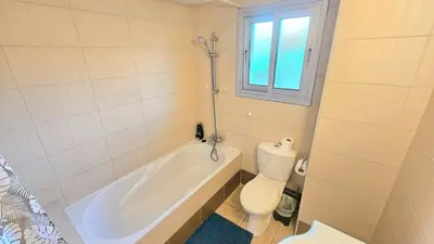 a bathroom with a tub and a toilet and a window at Neapolis city apartment in Limassol