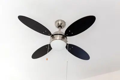 a ceiling fan with black blades on a white ceiling at Modern Larnaca Beach Apartment in Larnaka