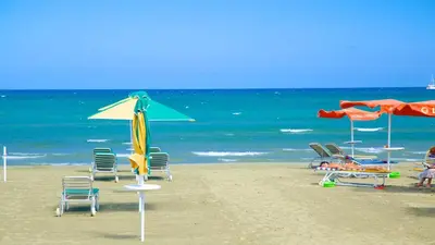 a group of chairs and umbrellas on a beach at Modern Larnaca Beach Apartment in Larnaka