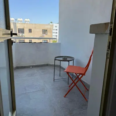 a red chair and a table on a balcony at Luxurious Penthouse in Larnaca Center 300m From The Beach in Larnaka