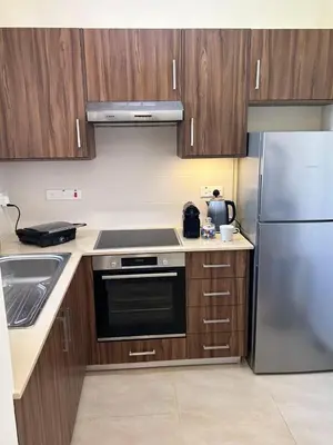 a kitchen with wooden cabinets and a stainless steel refrigerator at Cozy 2-Bedroom Beach Flat in Paralimni