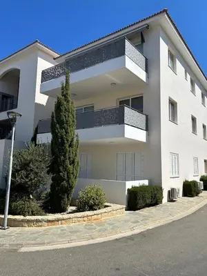 a white apartment building with a tree in front of it at Cozy 2-Bedroom Beach Flat in Paralimni