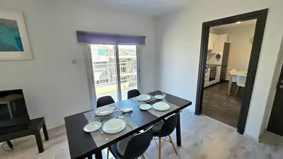 a dining room with a table and chairs with plates on it at Molos city centre living in Limassol