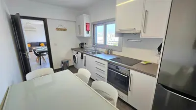 a kitchen with white cabinets and a table and chairs at Molos city centre living in Limassol