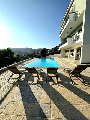 a swimming pool with two chairs next to a building at Serenity Pool & Garden Villa in Limassol