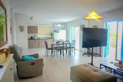 a living room with a flat screen tv and a kitchen at Kapparis Avenue Beach Apartment in Paralimni
